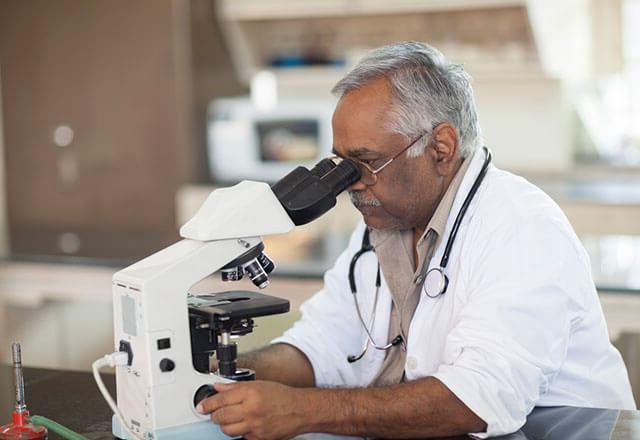 一位老人正在用显微镜做研究